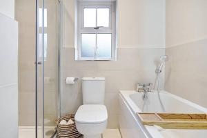 La salle de bains est pourvue de toilettes, d'une baignoire et d'une fenêtre. dans l'établissement Stylish 1 Bed Townhouse, à Culmore