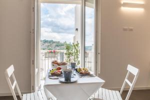 a white table with a plate of food on it with a window at Terrazza Dei Sogni in Ragusa