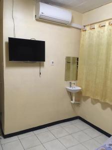 a bathroom with a sink and a tv on the wall at Hotel Mangueira in Paramaribo
