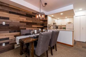 a kitchen and dining room with a wooden wall at Creekside Slopeside 1BR with pool, hot tub, BBQ in Whistler