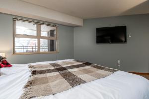 a bedroom with a bed with a checkered blanket on it at Creekside Slopeside 1BR with pool, hot tub, BBQ in Whistler