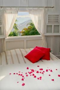 een bed met roze bloemen en een raam bij La Petite Villa Guadeloupe in Sainte-Anne