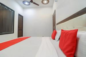 a bedroom with a large white bed with red pillows at OYO 65320 Hotel Surya in Sāmāna