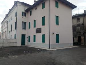 a large white building with green windows in a parking lot at Residence Montegrappa in Sandrigo