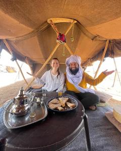 a man and a woman sitting at a table in a tent at Roses desert camp in Merzouga