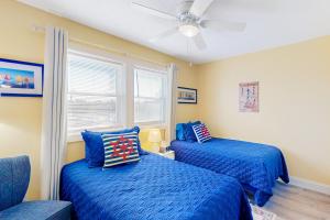 1 dormitorio con 2 camas azules y ventilador de techo en Sunset Terrace, en Avon