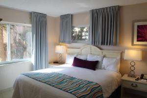 a bedroom with a large bed and two windows at Canada House Beach Club Resort in Pompano Beach