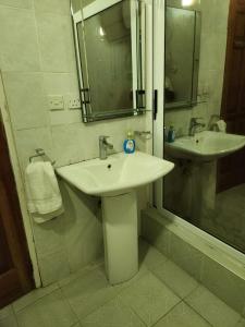ein weißes Bad mit 2 Waschbecken und einer Dusche in der Unterkunft Osu Apartment in Accra