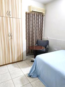 ein Schlafzimmer mit einem Bett, einem Tisch und einem Stuhl in der Unterkunft Osu Apartment in Accra