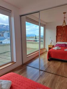 Schlafzimmer mit einem roten Bett und einem großen Fenster in der Unterkunft Lo de Moli 5A in Ushuaia