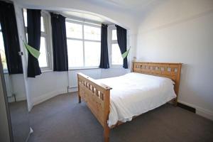 ein Schlafzimmer mit einem Holzbett und einem Fenster in der Unterkunft Spacious and bright 4 bed home in vibrant Chorlton in Manchester