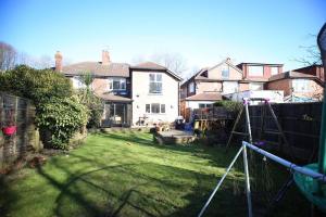 a backyard of a house with a yard with a playground at Spacious and bright 4 bed home in vibrant Chorlton in Manchester