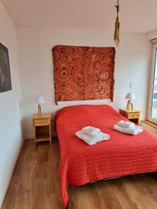 1 dormitorio con 1 cama roja y 2 toallas en Lo de Moli 5A en Ushuaia