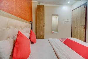 a bedroom with a bed with red pillows at OYO 67027 Grace Inn in Mumbai