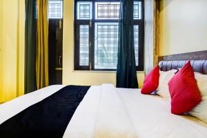 a bedroom with a bed with red and black pillows at Capital O 66972 Sangam Hotel And Resort in Kotdwāra