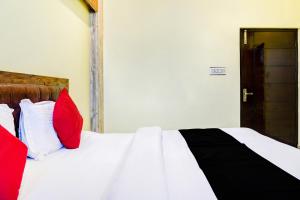 KotdwāraにあるCapital O 66972 Sangam Hotel And Resortのベッドルーム1室(赤と白の枕が備わるベッド1台付)