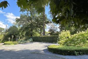 um jardim com arbustos e árvores e uma entrada em La Fauvette em Embourg