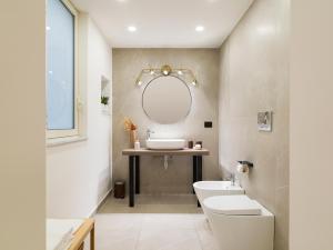ein Badezimmer mit einem Waschbecken, einem WC und einem Spiegel in der Unterkunft Kondo Maisons in Catania