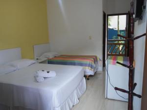 a room with two beds and a door to a balcony at Pousada Água Marinha in Caraguatatuba