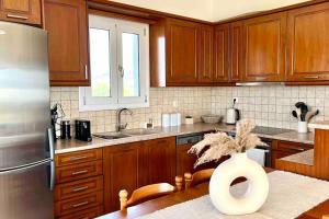 a kitchen with wooden cabinets and a vase with a plant in it at Villa Oinoni in Egina