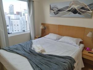 un perro blanco acostado en una cama en un dormitorio en Apartamento Vista Maravilhosa - Próximo da Paulista, en São Paulo