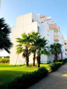a building with palm trees in front of it at Fantastique Appartement avec piscine sur la plage M2 in Tangier