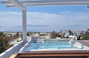 a hot tub on a balcony with a view of the ocean at Villa Pari Manda in Agios Prokopios