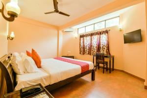 1 dormitorio con cama, escritorio y ventana en OYO 13415 Cherai Village Home Stay en Cherai Beach