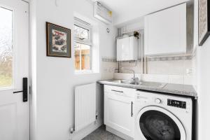 a laundry room with a washing machine and a sink at Luxurious 3 Bed House with Free Parking, Close to the Train Station & Town in Braintree