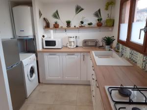 a kitchen with white cabinets and a sink and a stove at Studio " LE FARE DES TERRES ROUGES" Dans L AUDE in Arques