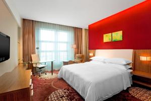 een slaapkamer met een groot bed en een rode muur bij Four Points by Sheraton Qingdao, Chengyang in Qingdao