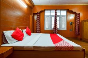 Un dormitorio con una cama con almohadas rojas y una ventana en OYO Flagship Hotel Unique en Shimla