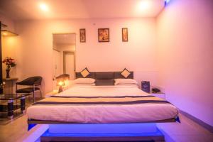 1 dormitorio con 1 cama grande con luces moradas en Capital O 5764 A Park Hotel en Gwalior