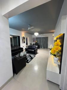 ein Wohnzimmer mit schwarzen Möbeln und gelben Blumen in der Unterkunft Fully Furnished Luxurious Terrace apartment in Pune