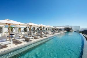 una piscina con tumbonas y sombrillas en Residential Retreat 1 Bedroom Suite Garza Blanca Resort & Spa, en Cabo San Lucas