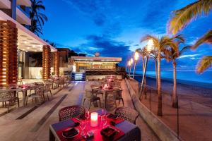 un restaurante en la playa con mesas y palmeras en Residential Retreat 1 Bedroom Suite Garza Blanca Resort & Spa, en Cabo San Lucas