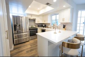 a kitchen with white cabinets and a stainless steel refrigerator at Beautiful Beverly Hills Townhome in Los Angeles