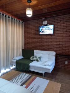 sala de estar con sofá y TV en una pared de ladrillo en Vivendas Canaã, en Espera Feliz