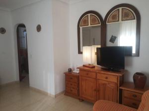 a living room with a television on a wooden dresser at Torremar vera playa naturista in Vera
