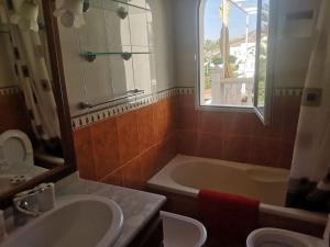 uma casa de banho com uma banheira e um lavatório e uma banheira em Torremar vera playa naturista em Vera