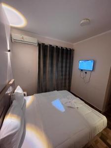 Schlafzimmer mit einem weißen Bett und einem TV an der Wand in der Unterkunft Cairo Casa Hostel in Kairo