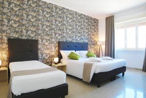 ローマにあるHH Vatica Suite IIのベッド2台と壁が備わるホテルルームです。