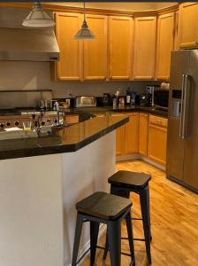 una cocina con armarios de madera y una barra con 2 taburetes en Home sweet home, en Hillsboro