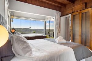 ein Schlafzimmer mit einem weißen Bett und einem großen Fenster in der Unterkunft Cabana Blaue Hütte Vila Germânica by Achei in Nova Petrópolis