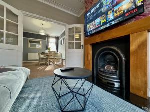 a living room with a table and a fireplace with a tv at Freeston House - Charm Townhouse in Cleethorpes