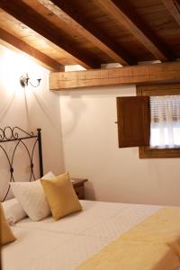 Un dormitorio con una cama con sábanas blancas y techos de madera. en Casa rural La Aldea, en Cabezuela del Valle