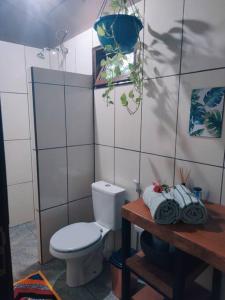 a bathroom with a toilet and a table with towels at Rosa dos Ventos Chalés in Cavalcante