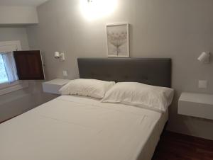 - un lit blanc dans une chambre avec une photo sur le mur dans l'établissement Barco, à Tolède