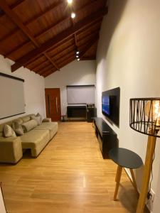 sala de estar con sofá y TV de pantalla plana en Apartamento Avenida en Camanducaia