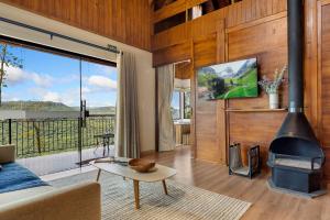 ein Wohnzimmer mit einem Kamin und einem großen Fenster in der Unterkunft Cabana Rote Hütte Vila Germânica by Achei in Nova Petrópolis